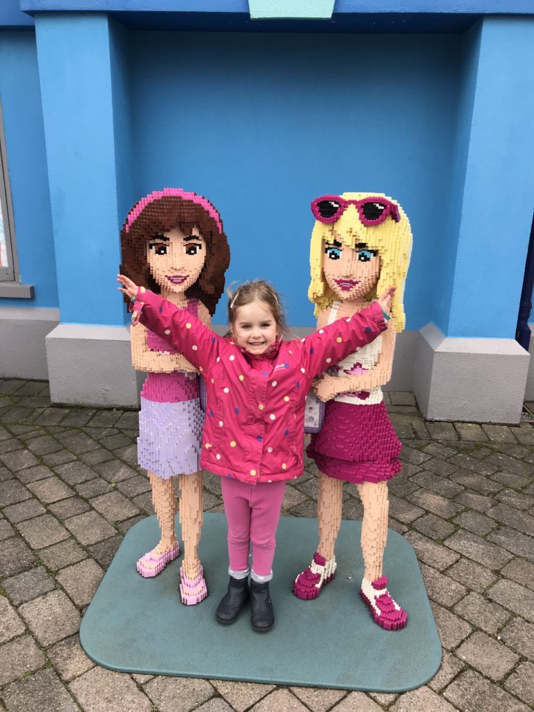 my daughter posing for another photo alongside some lego statues