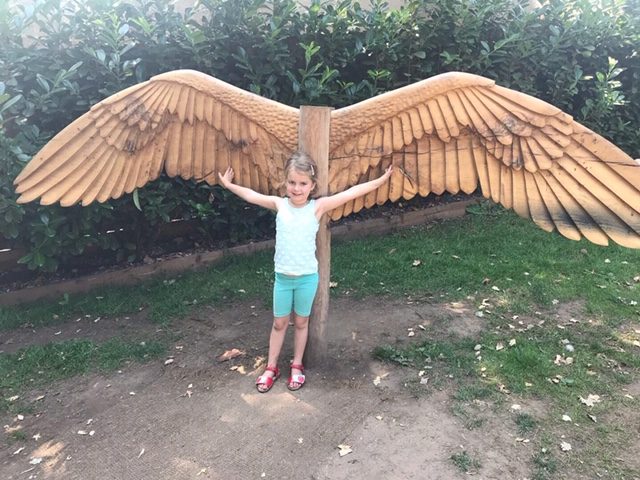 A girl by large bird wings