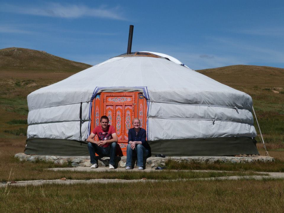 man and woman in front of yurt