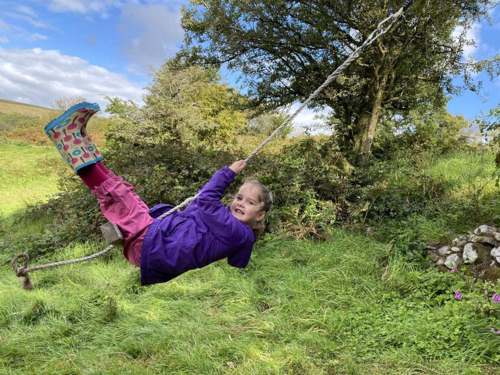 girl swinging on rope swing at Glamping Feather Down Farm