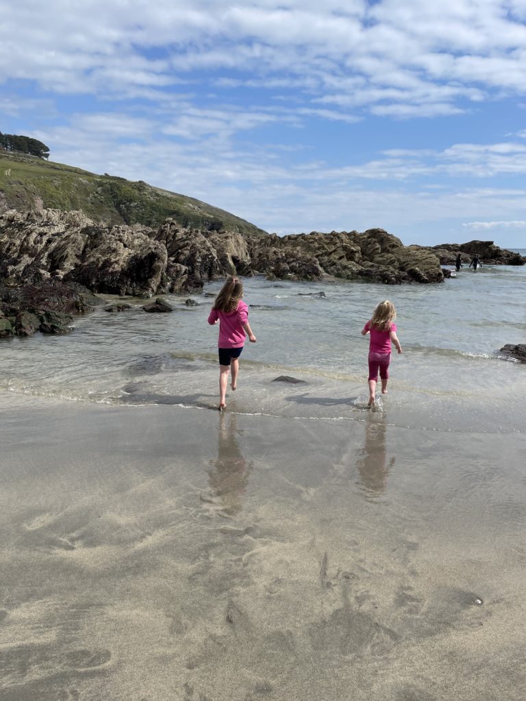 two girls running into the water at talland bay in south east cornwall