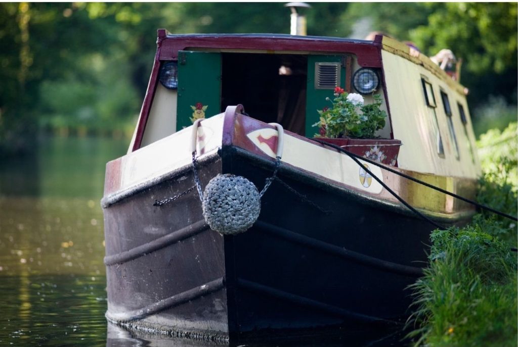 a red white and black narrowboat on a canal