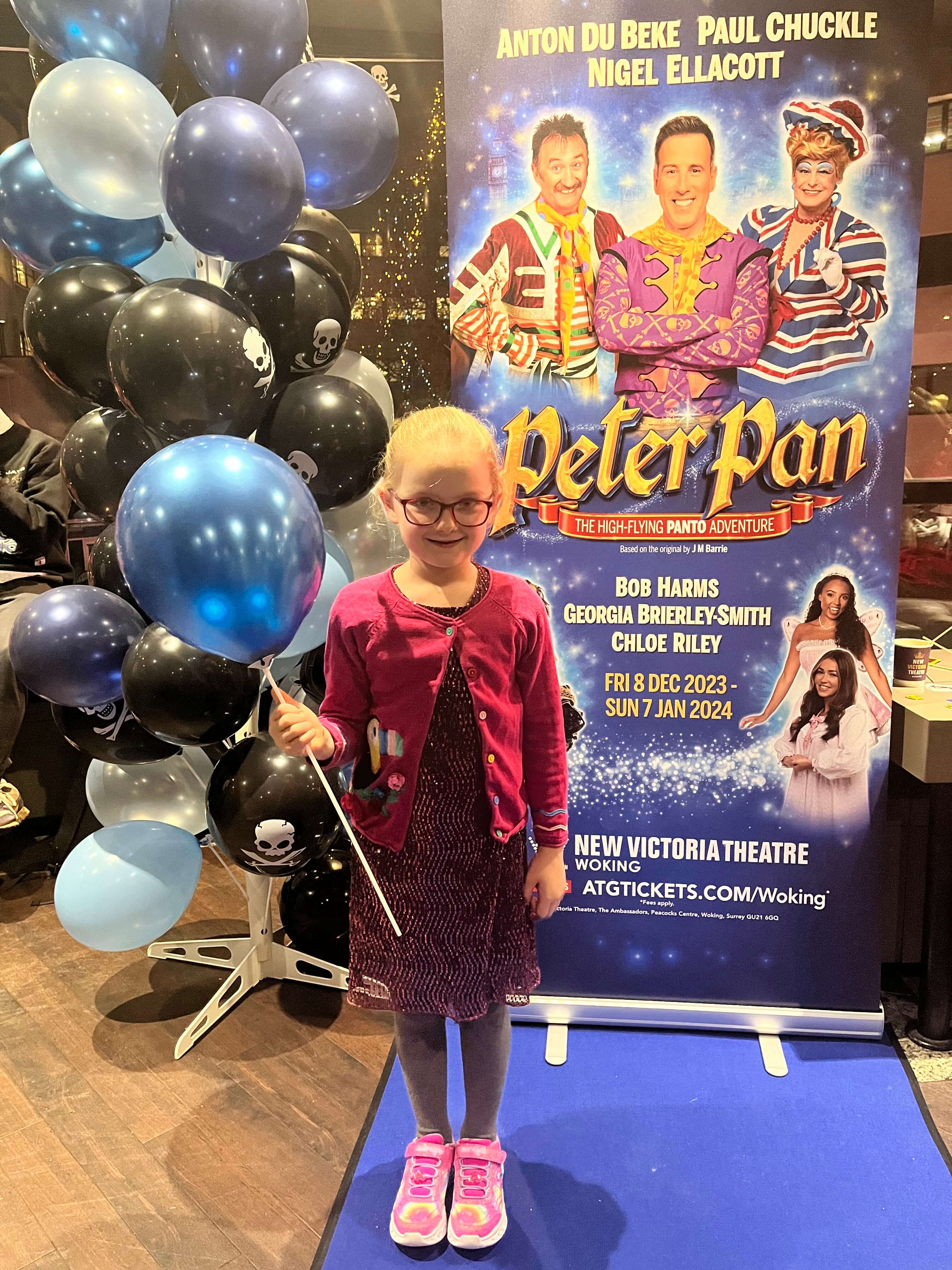 girl in front of peter pan sign holding a balloon